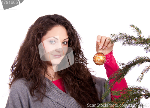 Image of beautiful brunette woman is decorating a christmas tree 