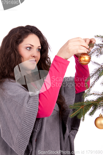 Image of beautiful brunette woman is decorating a christmas tree 