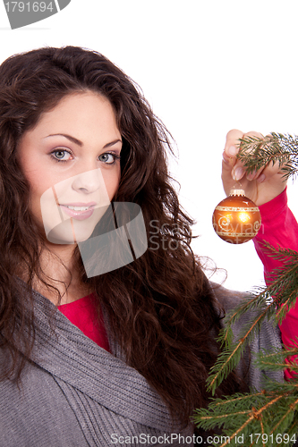 Image of beautiful brunette woman is decorating a christmas tree 