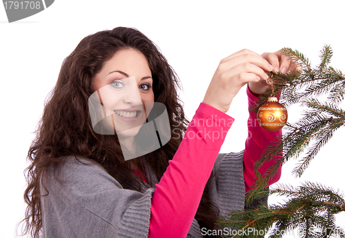 Image of beautiful brunette woman is decorating a christmas tree 
