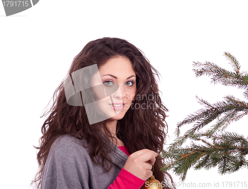 Image of beautiful brunette woman is decorating a christmas tree 