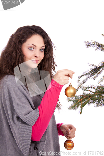 Image of beautiful brunette woman is decorating a christmas tree 