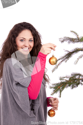 Image of beautiful brunette woman is decorating a christmas tree 