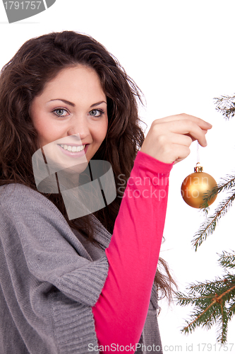 Image of beautiful brunette woman is decorating a christmas tree 