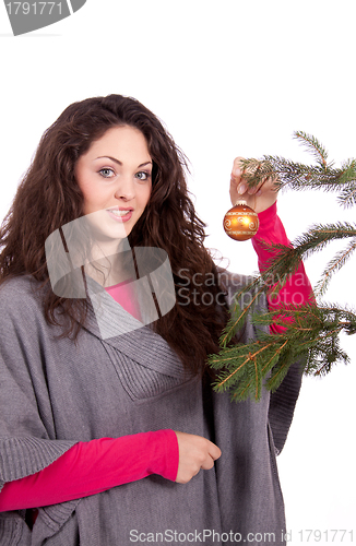 Image of beautiful brunette woman is decorating a christmas tree 