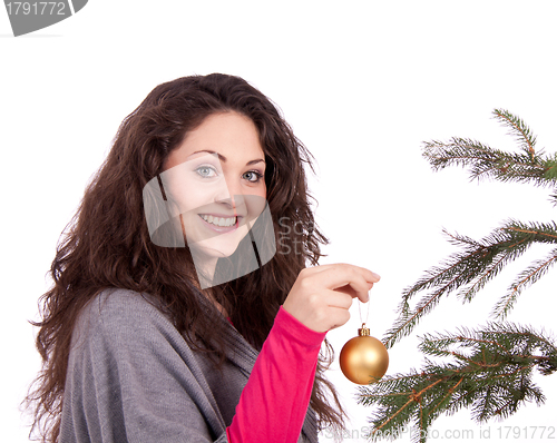 Image of beautiful brunette woman is decorating a christmas tree 