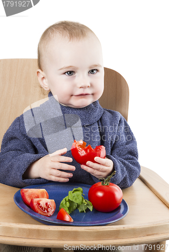Image of young child eating tomatoes in high chair