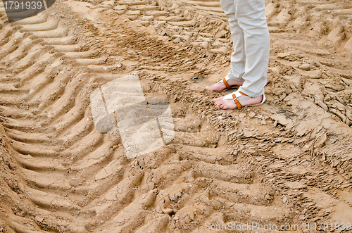 Image of woman legs stand on quarry sand truck tracks 