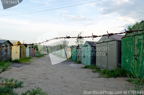 Image of Rusty metal car park garages fence in barbed wire 