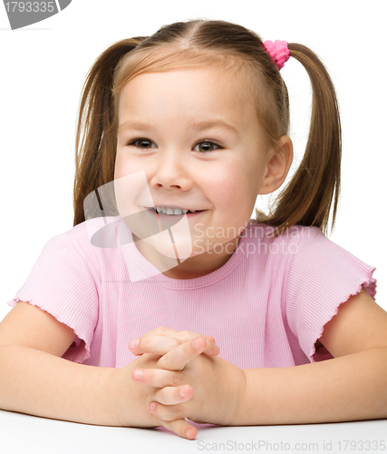 Image of Happy little girl sits at a table and smile