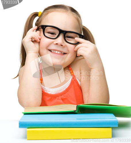 Image of Cute cheerful little girl reading book
