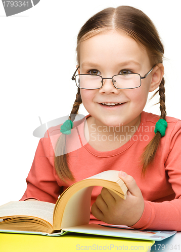 Image of Cute cheerful little girl reading book