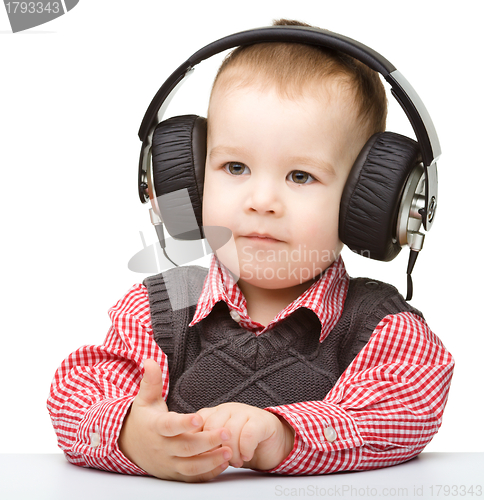 Image of Cute little boy enjoying music using headphones