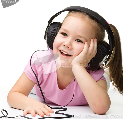 Image of Cute little girl enjoying music using headphones