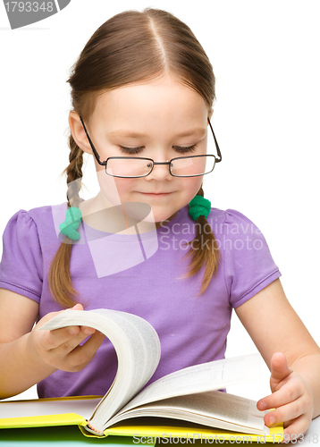 Image of Cute little girl reading book wearing glasses