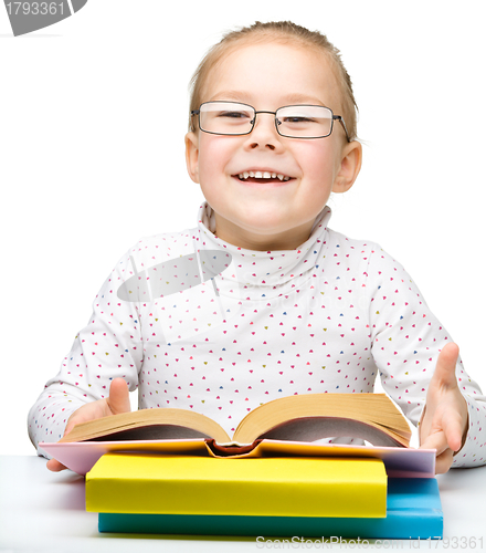 Image of Cute cheerful little girl reading book