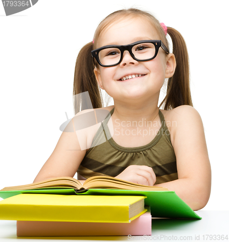 Image of Cute cheerful little girl reading book