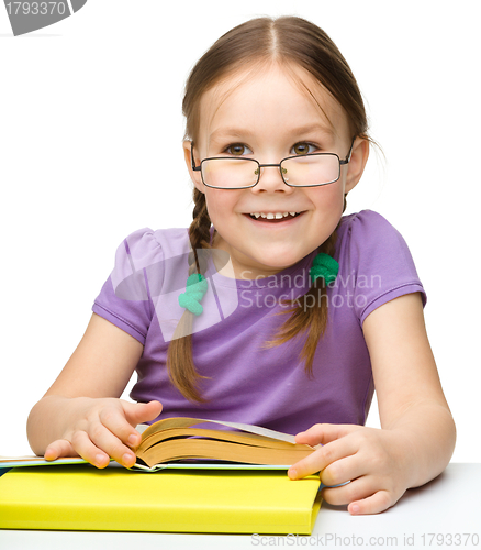 Image of Cute cheerful little girl reading book