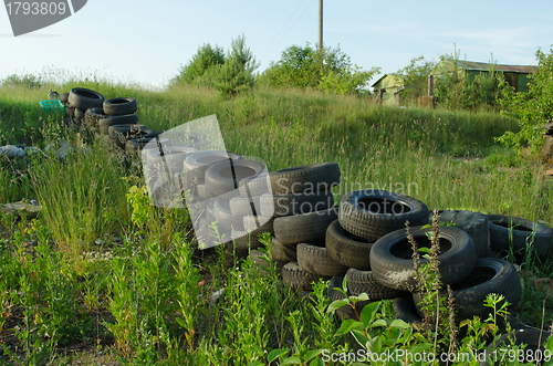 Image of Fence of old used tires in meadow. Pollution 