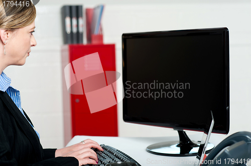 Image of Female executive typing and looking at lcd screen