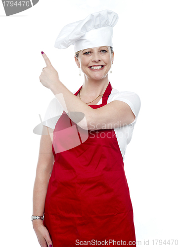 Image of Smiling female cook pointing away