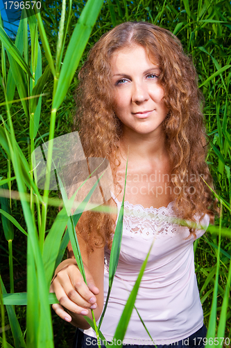 Image of beautiful girl in pink among high green grass of summer meadow