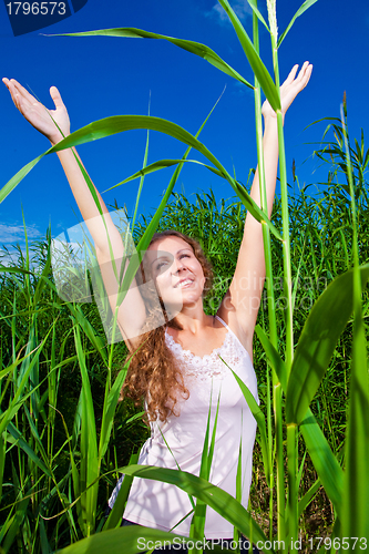 Image of beautiful girl in pink among high green grass of summer meadow