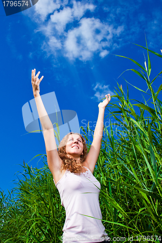 Image of beautiful girl in pink among high green grass of summer meadow