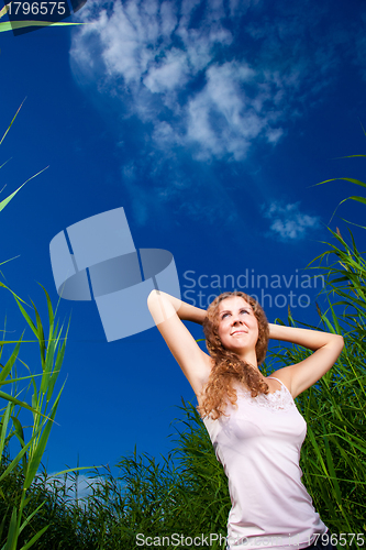 Image of beautiful girl in pink among high green grass of summer meadow