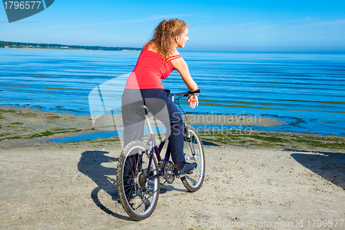 Image of beautiful woman with bicycle at the sea