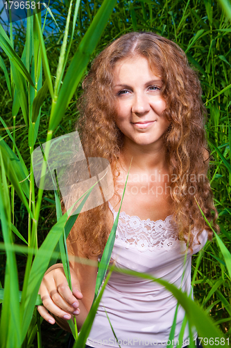 Image of beautiful girl in pink among high green grass of summer meadow