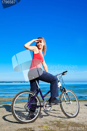 Image of beautiful woman with bicycle at the sea