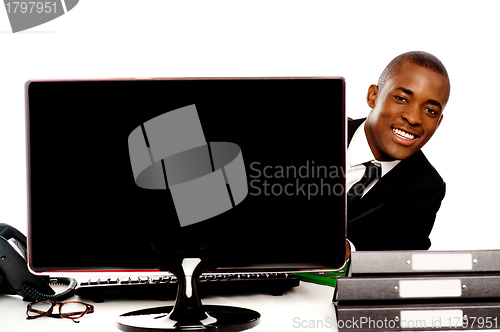 Image of Businessman peeping from behind lcd monitor