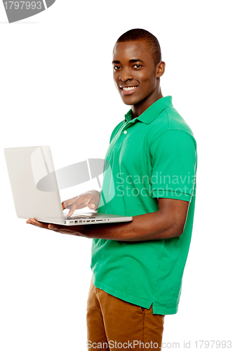 Image of Cool teenage guy surfing internet on laptop