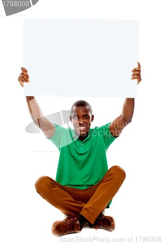Image of Seated young man holding white blank banner