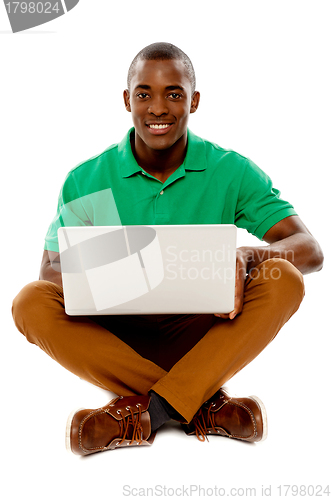 Image of Cool guy seated on floor using laptop