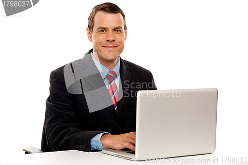 Image of Male executive at work desk operating laptop