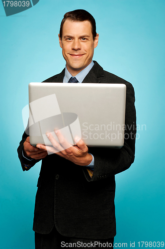 Image of Attractive businessman holding laptop