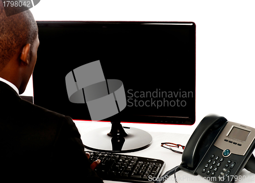 Image of Rear view of male executive working on pc