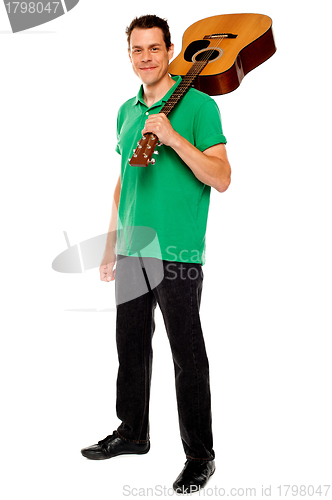 Image of Casual music lover carrying guitar on his shoulders