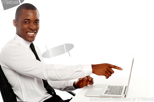 Image of Smiling young african indicating on laptop screen