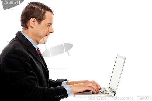 Image of Side view of corporate male typing on laptop