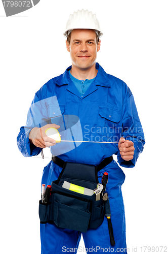 Image of Male worker stretching measuring tape