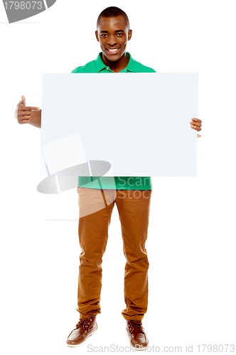 Image of Casual young guy pointing towards placard