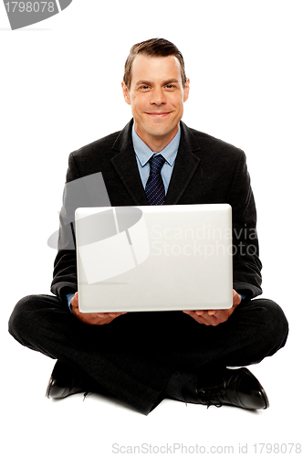 Image of Male executive with laptop sitting on the floor