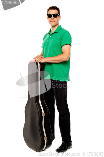 Image of Trendy young man posing with guitar case