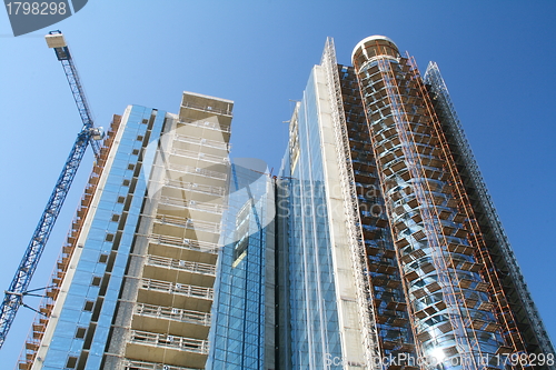 Image of Modern high-rise building under construction and a crane.  