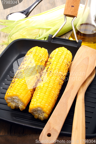 Image of  Grill corn and spatula in frying pan.