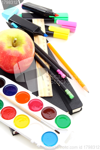Image of Pencils, pens and a notebook with an apple on a white background