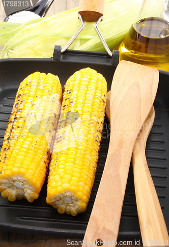 Image of Corn on the grill pan and wooden spoon.